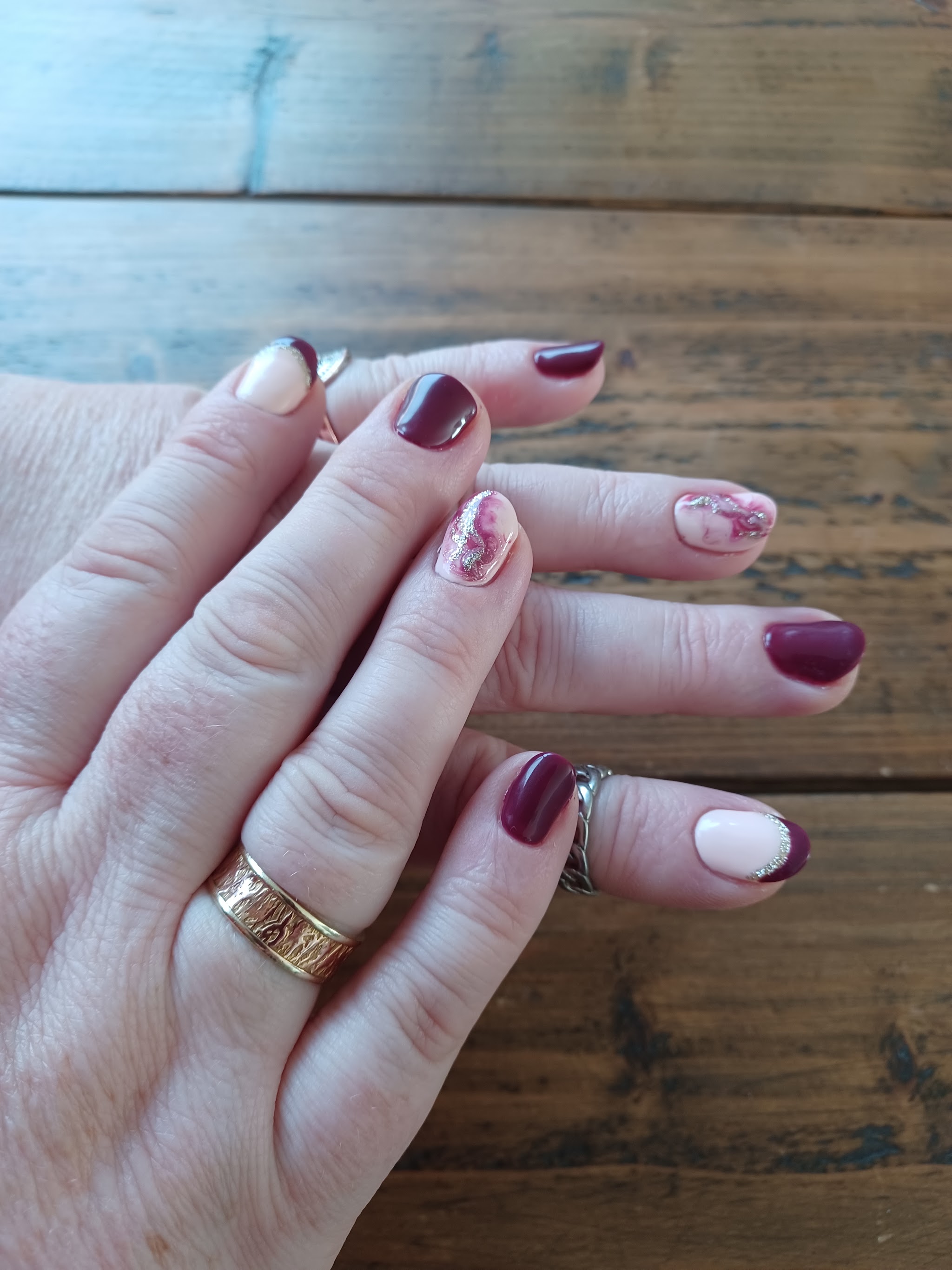 Bordeauxrode nagels met bloemetjes op een houten tafel